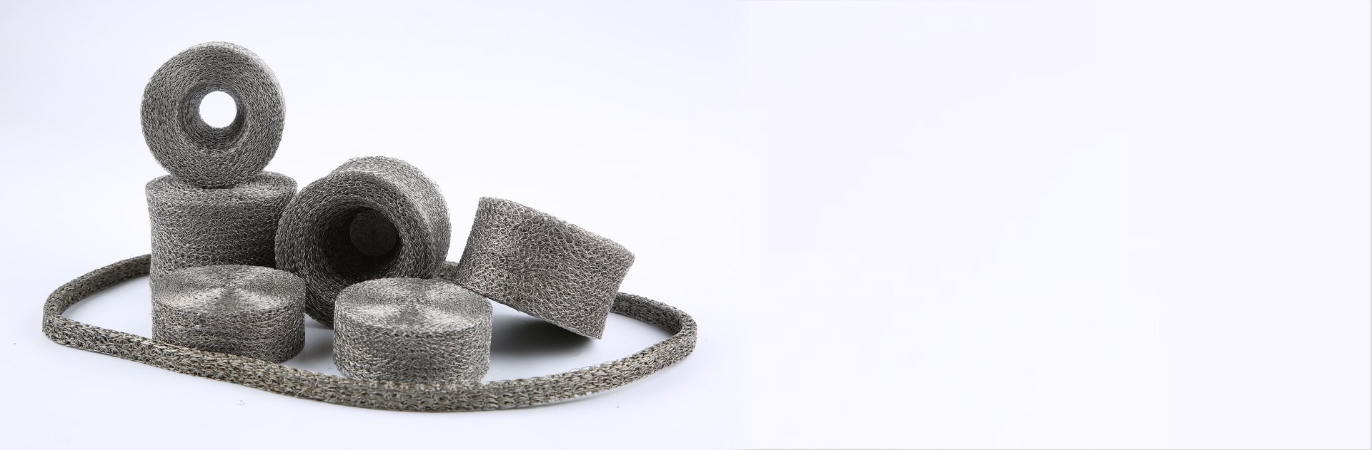 Several different shapes and specs of compressed knitted mesh on the gray background.