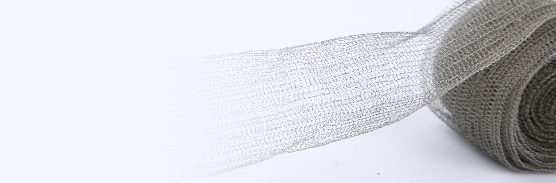 A roll of mono-filament stainless steel knitted mesh with a part stretching out.