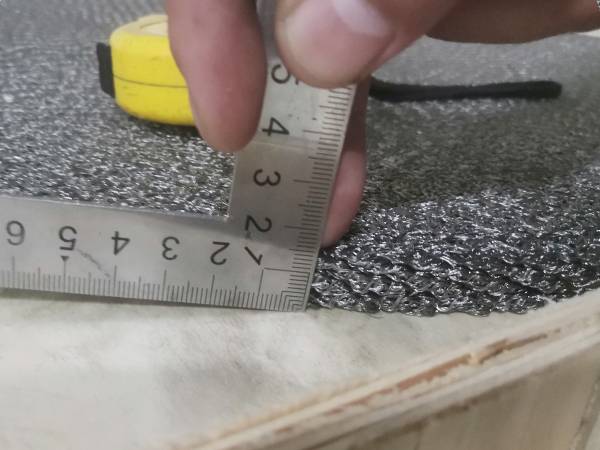 A try square is used to check the thickness of compressed knitted mesh.