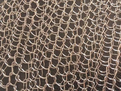 A mono-filament copper knitted mesh on the gray background.