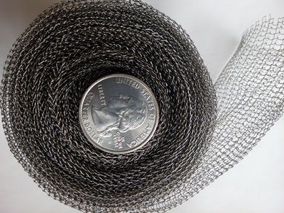 A small roll of stainless steel knitted mesh with a metal coin in the roll core.