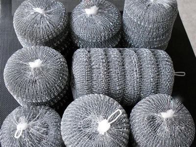 Six knitted cleaning balls in a net bag ans several net bags on the table.