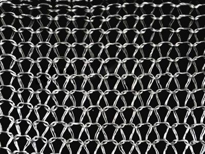 Un morceau de treillis métallique tricoté à plusieurs filaments sur fond noir.