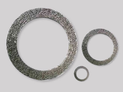 Three different diameter compressed knitted mesh gasket on the gray background.