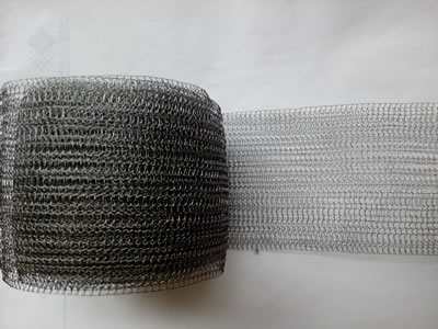 A roll of flatten stainless steel knitted mesh on the ground.